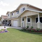 Navy family members relax on their front lawn while movers deliver household goods to their new home on Ford Island. Credit US Navy.